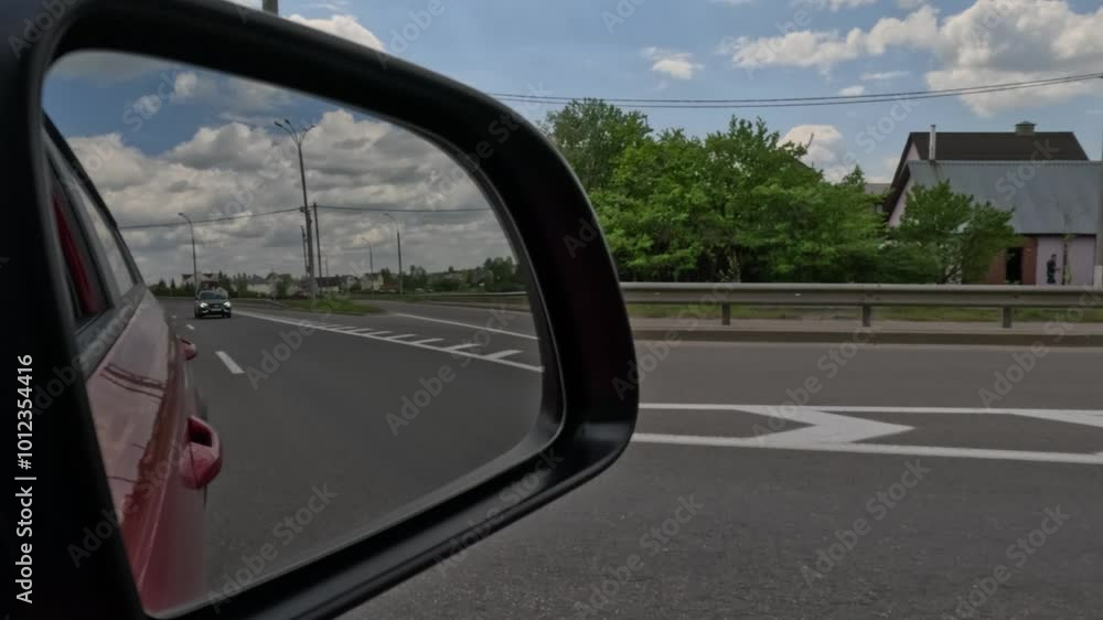 Red automobile in motion. View in the rear view side mirror of a auto, driving a red car along the track Red automobile in motion. View in the rear view side mirror of a auto, driving a red car along the track