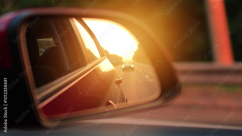 The sun is reflected in the mirror and window, evening road. View in the side rear view mirror of a car driving along the highway, in a red car The sun is reflected in the mirror and window, evening road. View in the side rear view mirror of a car driving along the highway, in a red car