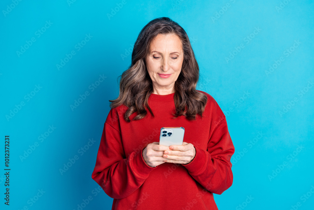 Portrait of nice aged woman use smart phone wear red sweater isolated on blue color background Portrait of nice aged woman use smart phone wear red sweater isolated on blue color background