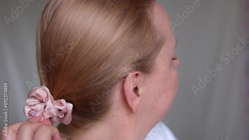 let hair down Pretty blond female with long hair take off scrunchie, let down hair during everyday beauty routine, back view