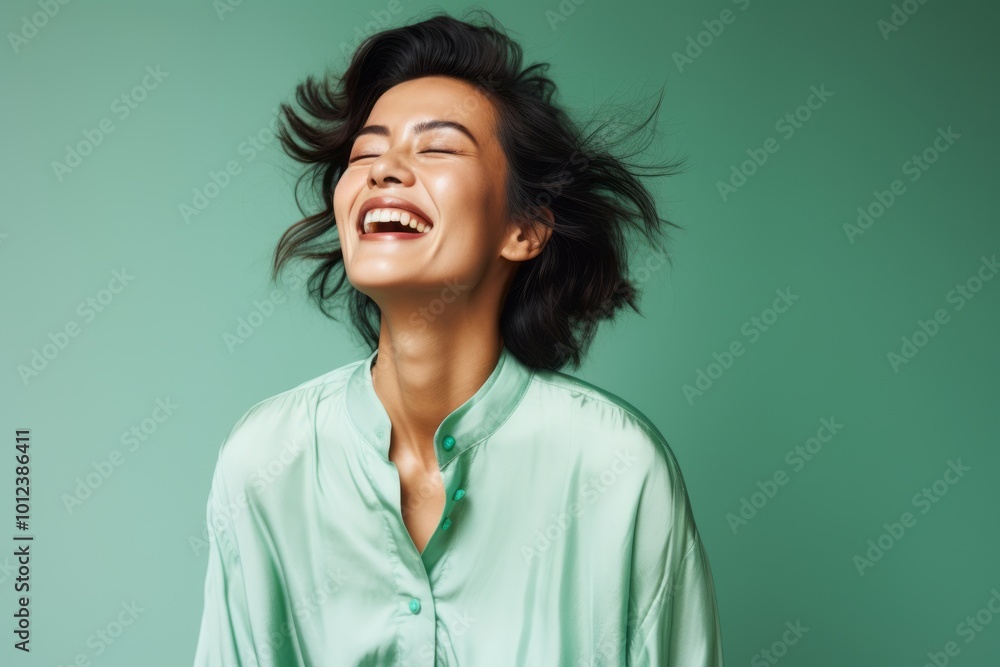 Beautiful young asian woman laughing and looking at camera on green background Beautiful young asian woman laughing and looking at camera on green background