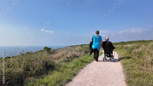 Devon England UK. 30.09.2024. Video. Elderly man using an electric wheelchair along a coastal pth in south Devon UK. photo