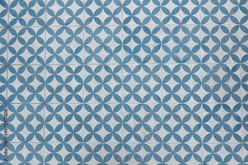 A detailed view of traditional Portuguese azulejos flooring, featuring a symmetrical geometric blue and white pattern. The repeating design highlights the beauty of handcrafted ceramic tiles.