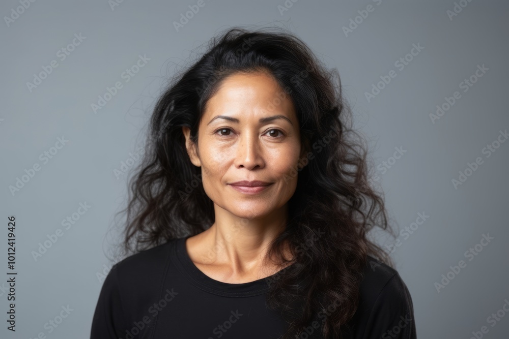 Portrait of a happy mature woman smiling at the camera against a grey background Portrait of a happy mature woman smiling at the camera against a grey background