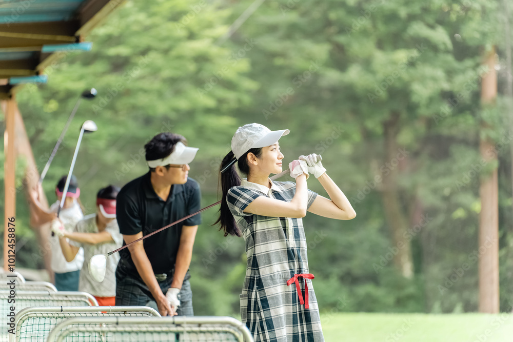 Obraz premium ゴルフ練習場・打ちっぱなし・ゴルフセンターでスイングの練習するゴルフ選手・ゴルファーの男女 
