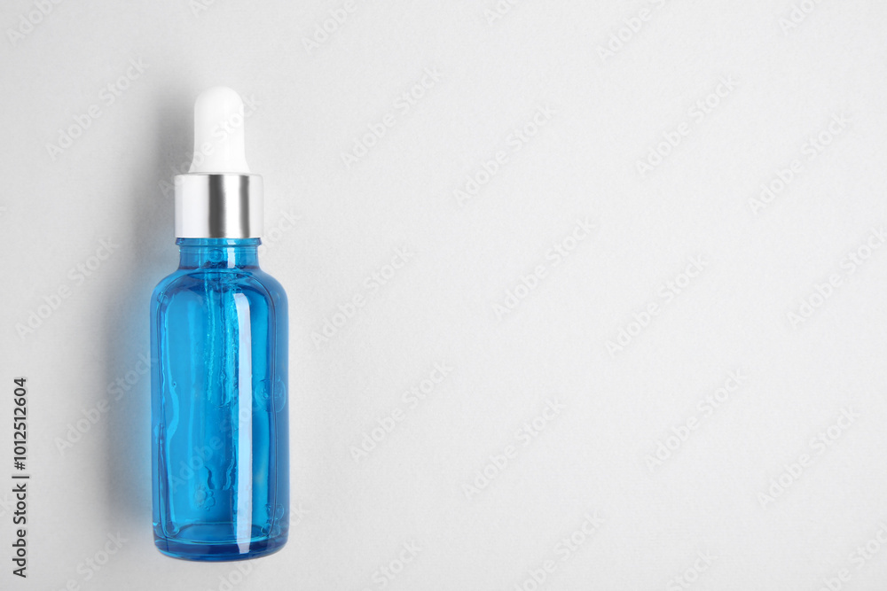 Essential oils in bottle on light background, top view. Space for text Essential oils in bottle on light background, top view. Space for text