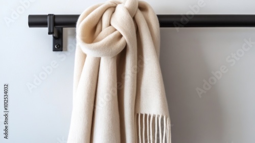 White Scarf with Fringed Ends Hanging on a Black Rod photo