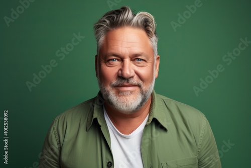 Portrait of a senior man with grey hair and beard on green background