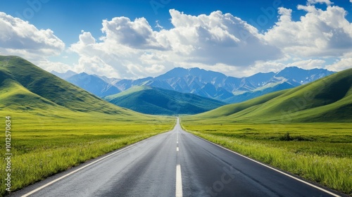 A long asphalt road leading into green mountains, with a bright sky and scattered, fluffy clouds on a sunny afternoon.