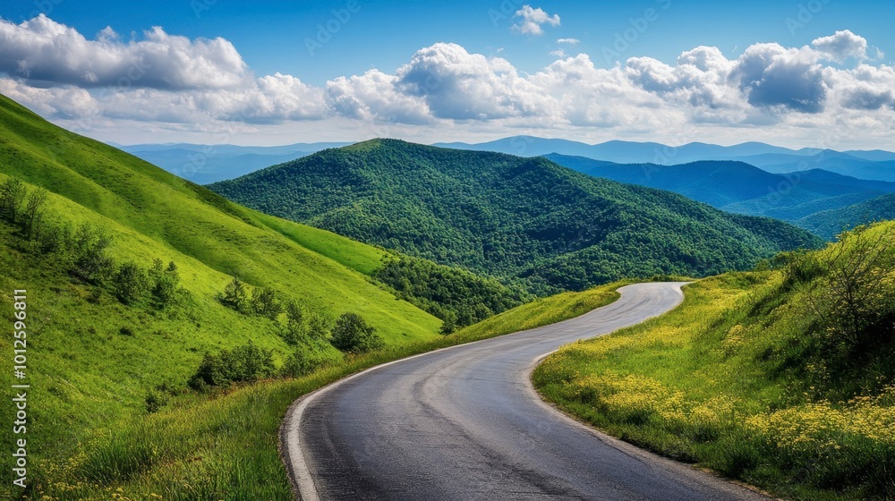 A winding asphalt road through green mountain valleys, with a clear blue sky and soft, fluffy clouds on a sunny day. A winding asphalt road through green mountain valleys, with a clear blue sky and soft, fluffy clouds on a sunny day.
