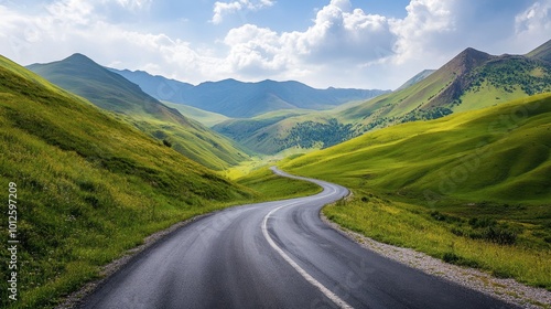 A winding asphalt road through vibrant green mountains, with a bright sky and gentle white clouds on a sunny afternoon.