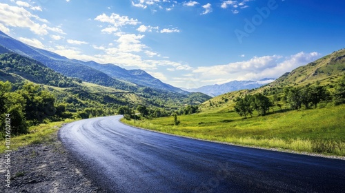 An asphalt road winding through green mountain valleys, with a clear blue sky and scattered clouds on a sunny day.