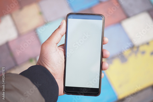 A smartphone in hand rests on a colorful paved surface, creating an inviting scene