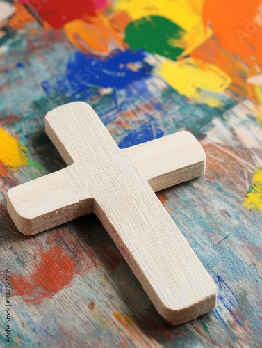 A simple wooden cross sits on a colorful background perfect for Vacation Bible School crafts.  This image represents faith, hope, and love.