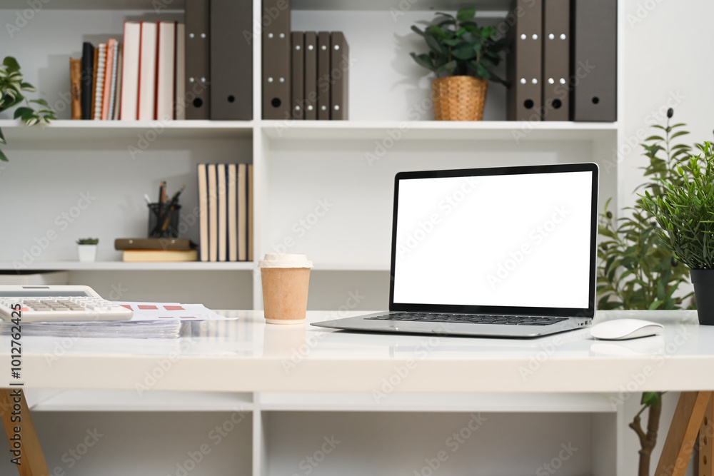 A laptop computer with empty display and office supplies on a desk in front of a bookshelf A laptop computer with empty display and office supplies on a desk in front of a bookshelf