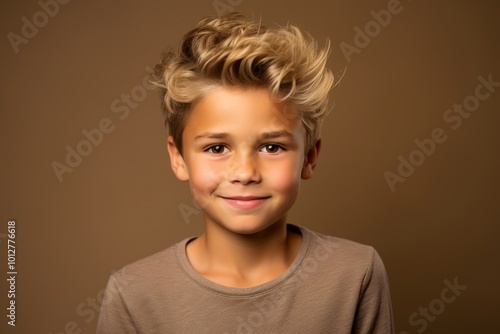 Portrait of a cute little boy with blond hair on brown background