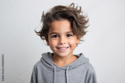 Portrait of a cute little boy with curly hair on grey background