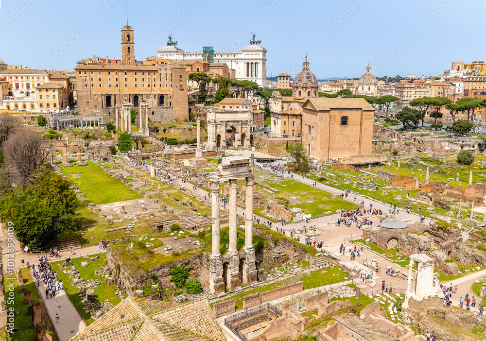 Fototapeta premium Rome, Italy - April 09, 2024: Ruins of the Roman Forum with tourists strolling among the archaeological remains in Rome, Italy