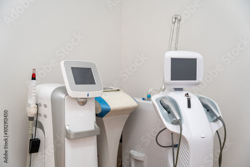 Advanced Aesthetic Technology: Two sleek, modern medical devices stand ready for use in a clean, clinical setting.  High-tech equipment for beauty and skincare treatments.