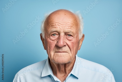 Portrait of a senior man looking at the camera on blue background