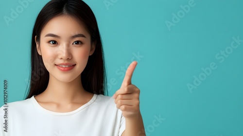 Asian woman presenting and pointing with copy space against a light blue background, showcasing beauty, confidence, and elegance