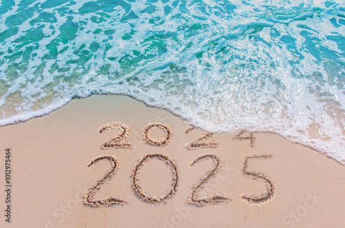 Message Year 2024 replaced by 2025 text written on beach sand background. Good bye 2024 - 2025 happy New Year coming concept.  top view.
