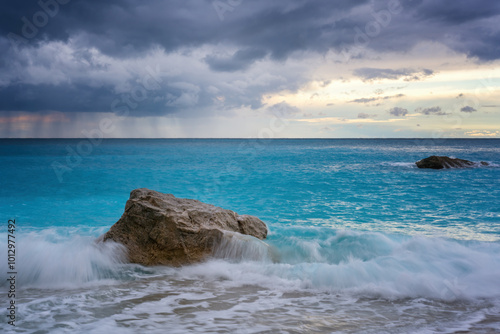 Waves crashing on a rock in the sea with turquoise water with a storm photo