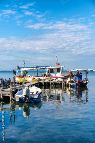 Fishing boats anchored on a pier at sunset, in Greece photo