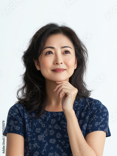 Thoughtful woman in casual dress, contemplating with gentle smile. Her expression reflects curiosity and introspection, set against light background