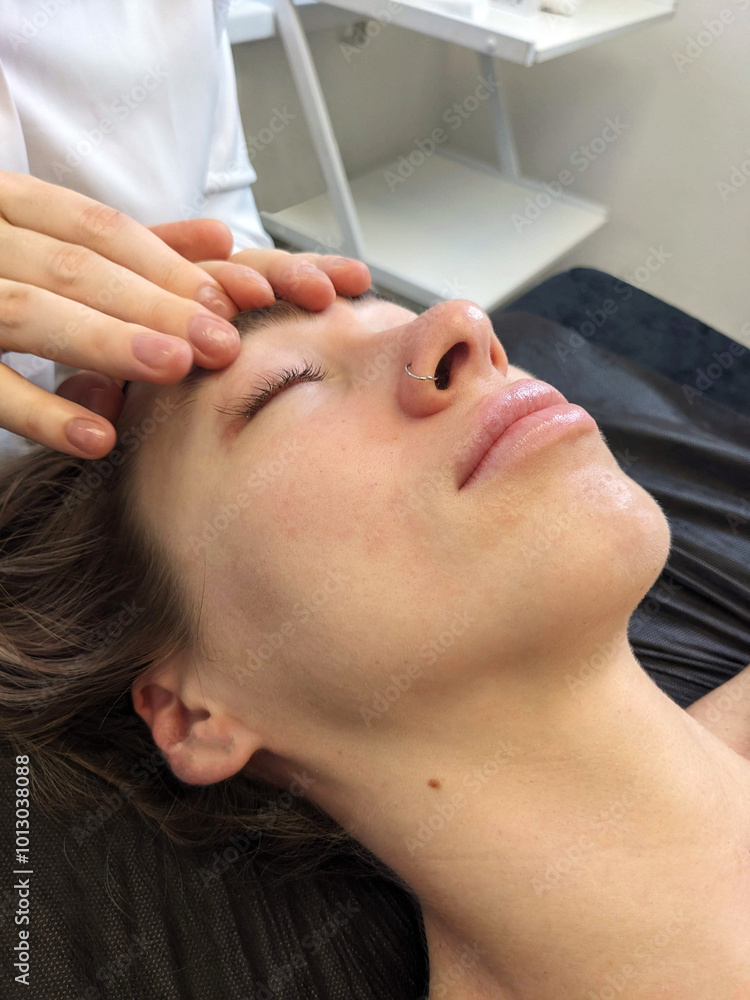 Naklejka premium Spa facial massage. A young European girl gets a face, neck and head massage. Cosmetic care, face washing.
