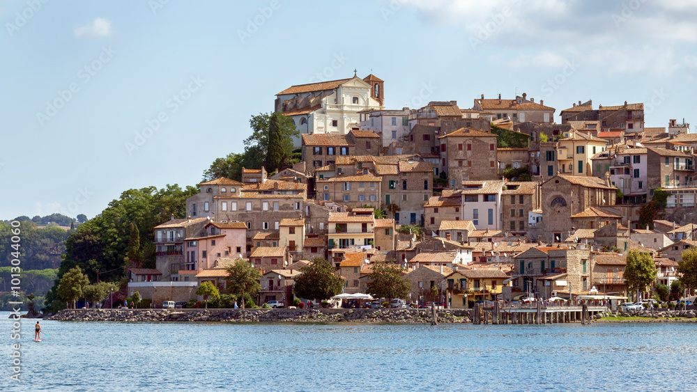 Fototapeta premium From the shores of Lake Bracciano rises up promontory in the lake and its picturesque medieval village of Anguillara Sabazia with its beautiful ancient architecture