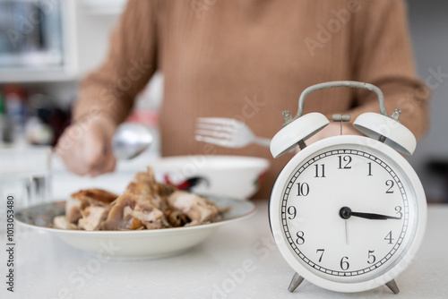 Billede på lærred Closeup of clock,woman eating breakfast in the afternoon,risk of gastritis,disea