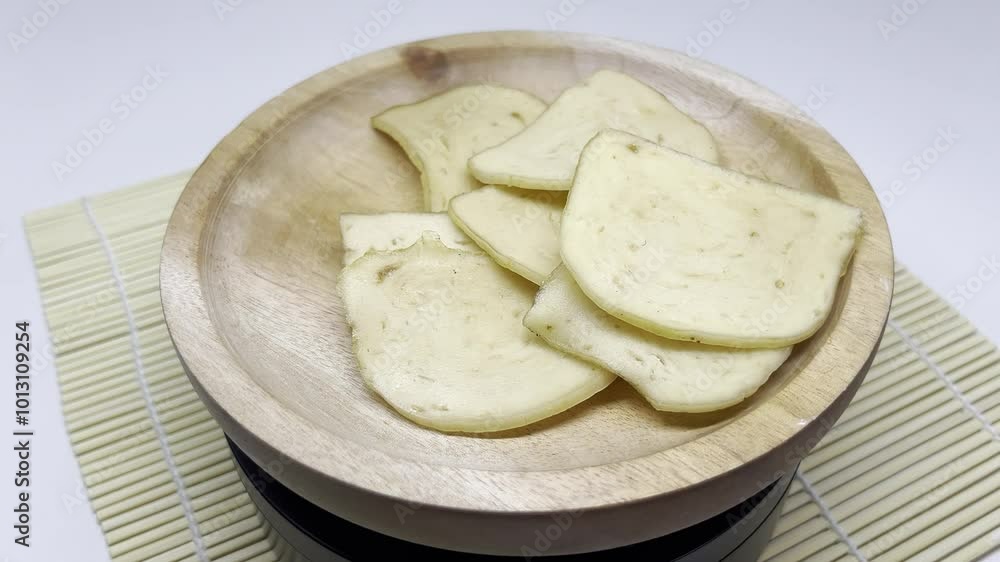 A wooden bowl filled with thinly sliced, light-colored food items. A wooden bowl filled with thinly sliced, light-colored food items.