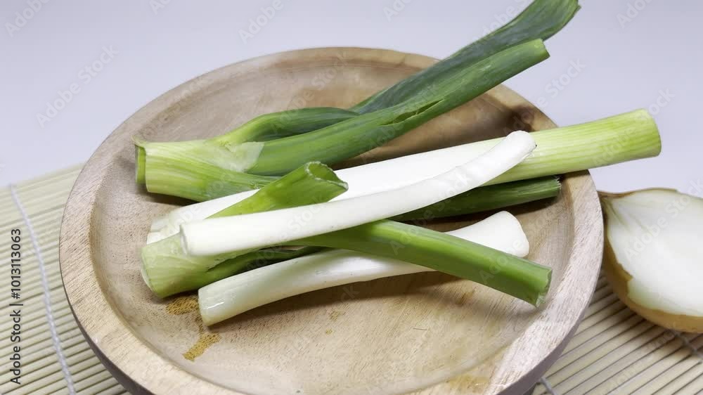 Fresh green onions arranged on a wooden plate, ready for cooking or garnishing dishes. Fresh green onions arranged on a wooden plate, ready for cooking or garnishing dishes.