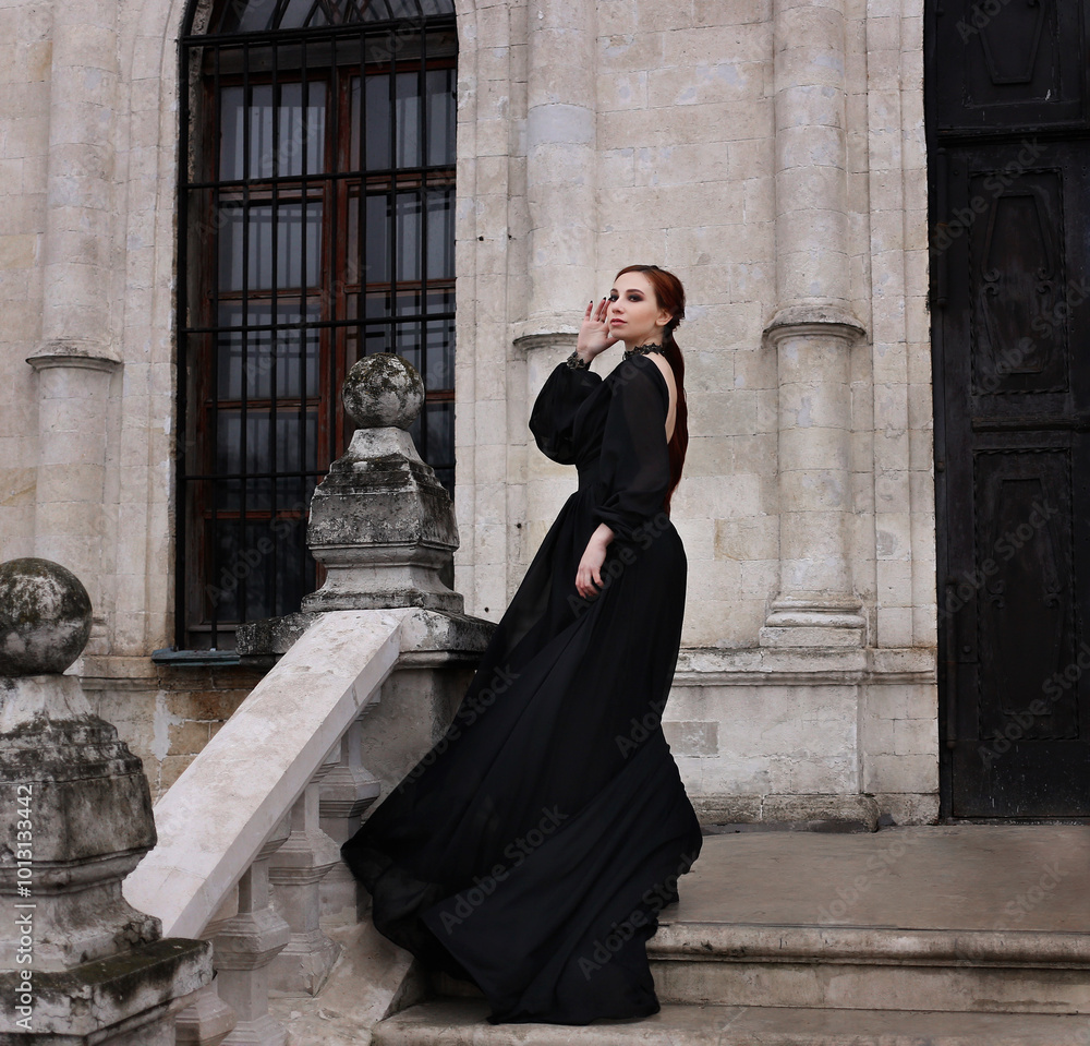 Φωτογραφία Young woman in long black dress on stone stairs of old gothic castle