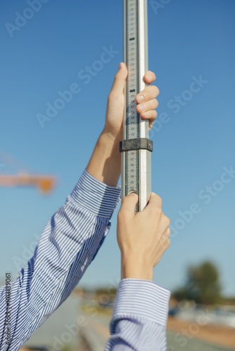 Worker is unfolding leveling rod on construction site.