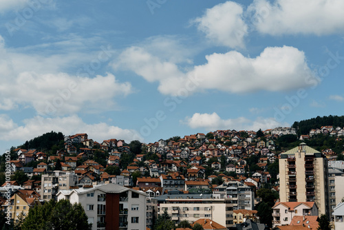 View of the old mountain houses with red tiled roofs and high-rise buildings in the Yugoslavian style. Small town Uzice in the south of Serbia. A sunny day, clouds in a blue sky. photo