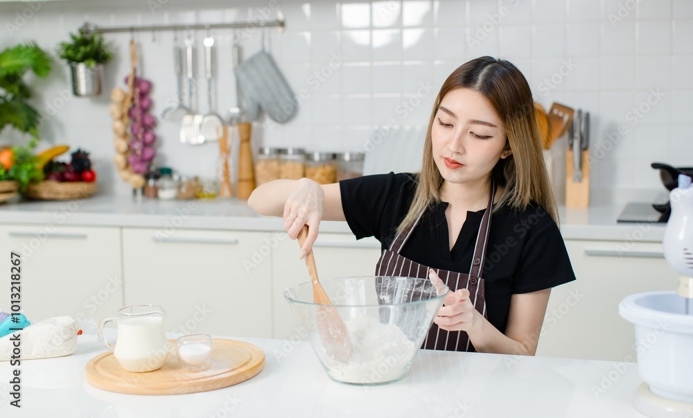 Young happy Asian beautiful woman, female wearing aprons intends to knead the dough mixing for baking cakes and making homemade bread and desserts. Lifestyle enjoy weekends cooking in kitchen at home Young happy Asian beautiful woman, female wearing aprons intends to knead the dough mixing for baking cakes and making homemade bread and desserts. Lifestyle enjoy weekends cooking in kitchen at home