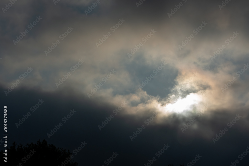 Moody evening sky with dramatic dark clouds and glowing sunlight breaking through. Moody evening sky with dramatic dark clouds and glowing sunlight breaking through.