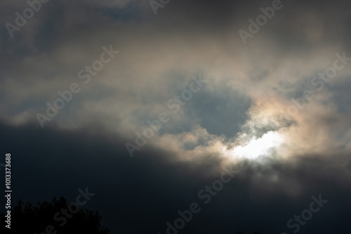 Moody evening sky with dramatic dark clouds and glowing sunlight breaking through.