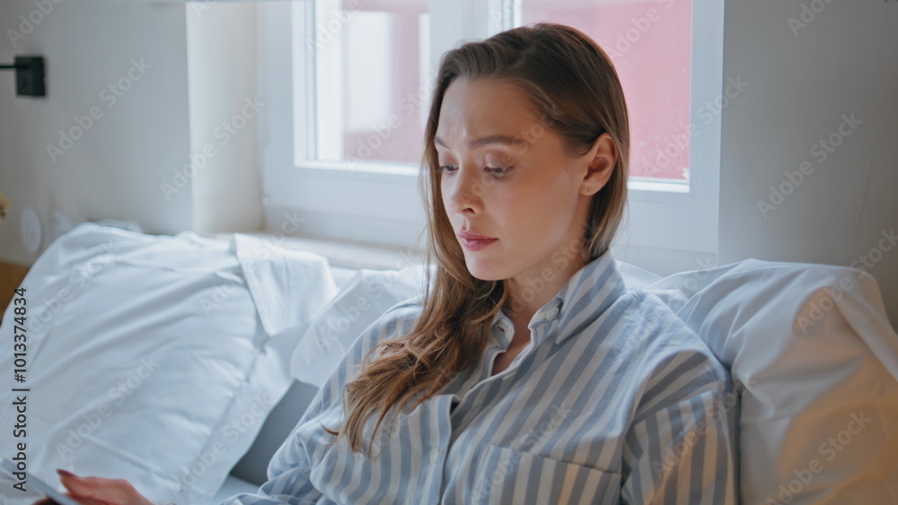 Thoughtful girl looking tablet in bed feeling worried closeup. Woman in bedroom Thoughtful girl looking tablet in bed feeling worried closeup. Woman in bedroom