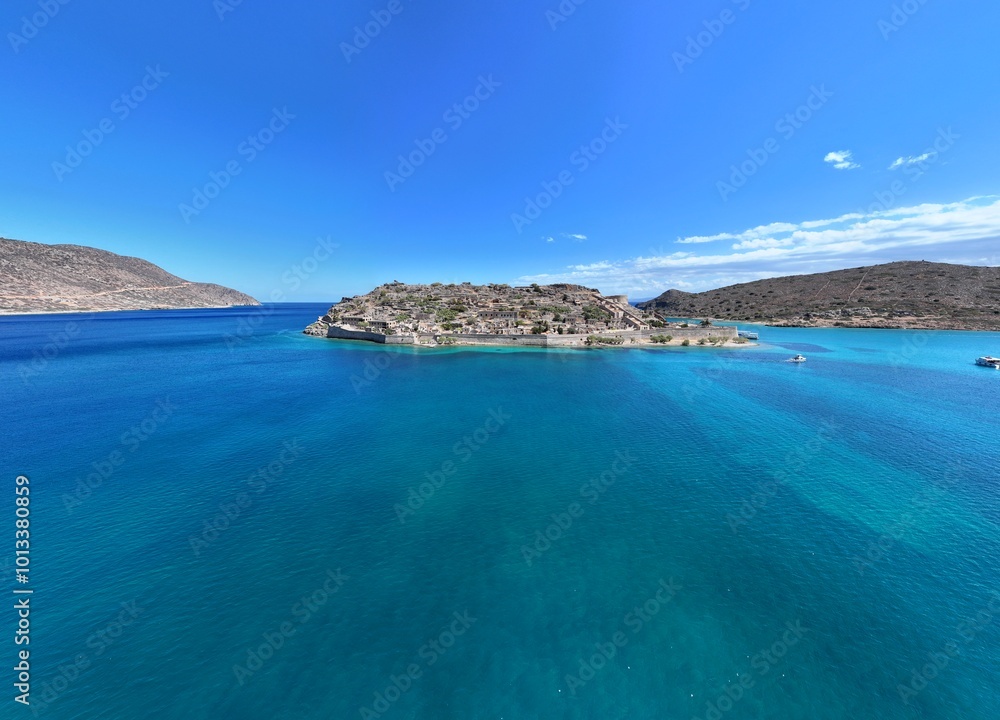 This aerial drone photo captures the beautiful Plaka Marina with its charming fishing boats, set against the backdrop of Spinalonga Island off the coast of Crete, Greece. The image highlights the This aerial drone photo captures the beautiful Plaka Marina with its charming fishing boats, set against the backdrop of Spinalonga Island off the coast of Crete, Greece. The image highlights the