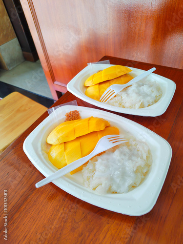 Kor Panich Mango Sticky Rice, a legendary dish from Thailand with ripe yellow mango slices and sticky rice topped with coconut milk. It conveys tropical sweetness, likely taken at an eye-level angle photo