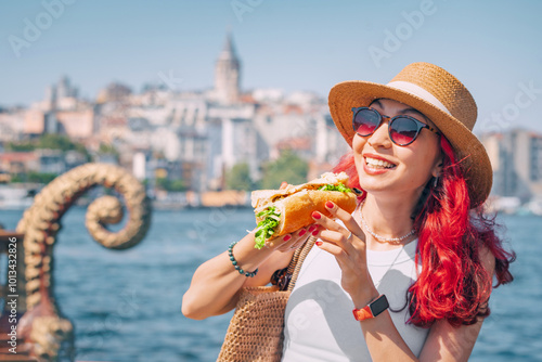 Obraz na płótnie A young woman enjoys a delicious balik ekmek sandwich at a street vendor in Istanbul, savoring the fresh grilled mackerel. w salonie