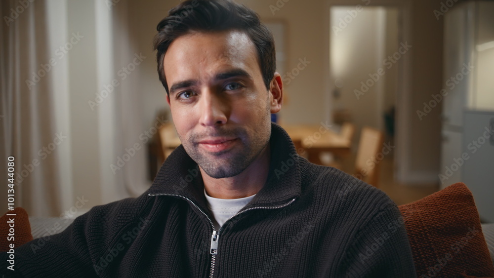 Obraz premium Handsome man sitting couch at evening living room closeup. Portrait smiling guy