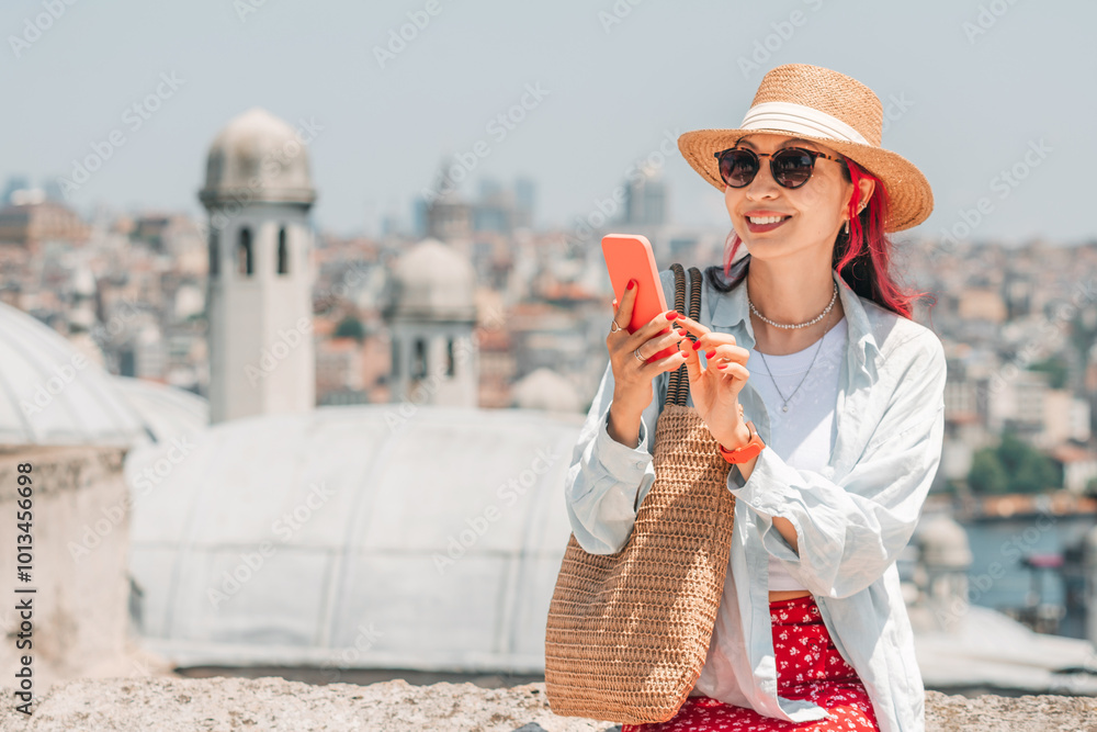 A stylish woman tourists in Istanbul, browsing her smartphone and checking a map while enjoying the sunny outdoor environment.
