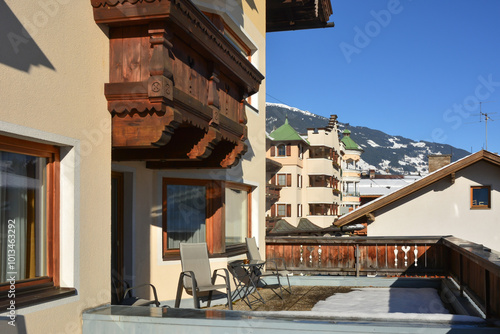 A large balcony made of carved wood of a winter ski hotel on which there are chairs for relaxation photo