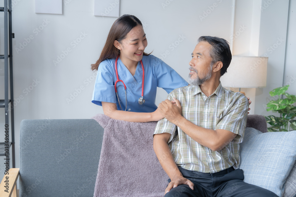Obraz premium Young nurse comforts an elderly man at home, showing care and trust. The patient looks happy and comforted as they sit together on a couch
