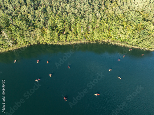 Aerial drone view of people kayaking on a lake surrounded by green forest. Kulka Reserve, Masuria, Poland. Sailing in red kayaks in the Masurian Lake District. Lake Lesk in the Kulka Reserve in Poland photo