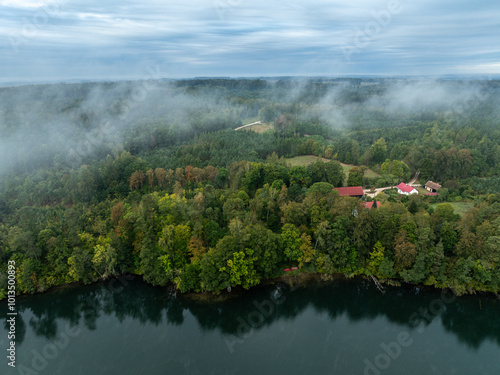 Aerial drone view of a lake surrounded by green forest. Big lake in the fog and clouds. Lake in the Masurian Lake District. Lake Lesk in the Kulka Reserve in Poland. Kulka Reserve, Masuria, Poland. photo